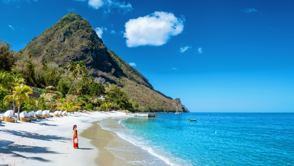 St Lucia Caribbean, woman on vacation at the tropical Island of Saint Lucia Caribbean Islands ocean, an Asian woman in red dress walking on the beach
