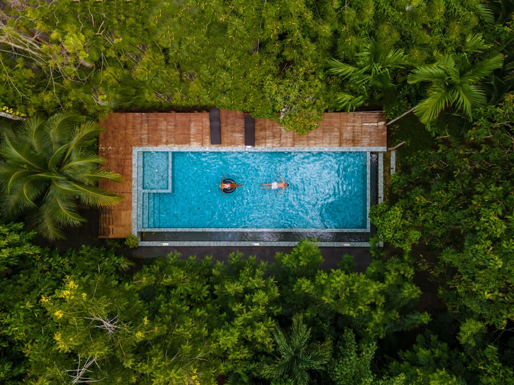 aerial drone view of swimming pool in the jungle of Krabi Thailand, aerial view with a drone above swimming pool in the jungle of Thailand. couple men and woman in pool from above
