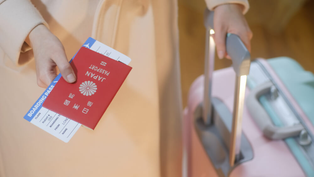 Fashion dressed girl with a suitcase holds Japan passport and boarding pass in her hand
