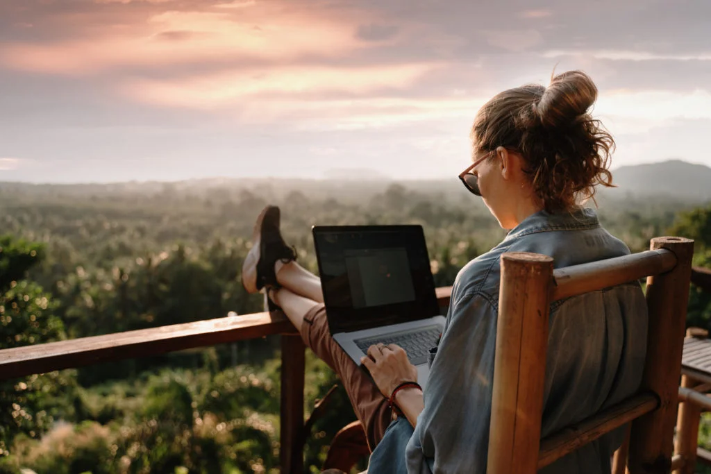 Young business woman working at the computer in cafe on the rock