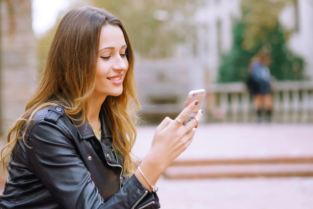 Side view portrait of happy women using smart phone outdoors checking her data plan