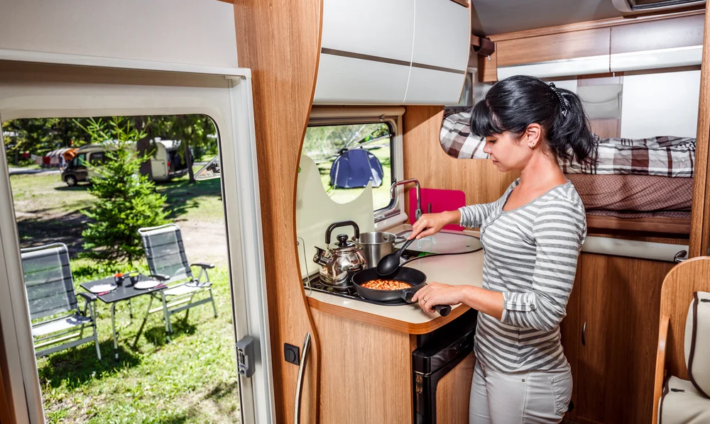 Woman cooking in camper, motorhome interior. Family vacation travel, holiday trip in motorhome, Caravan essentials car Vacation.
