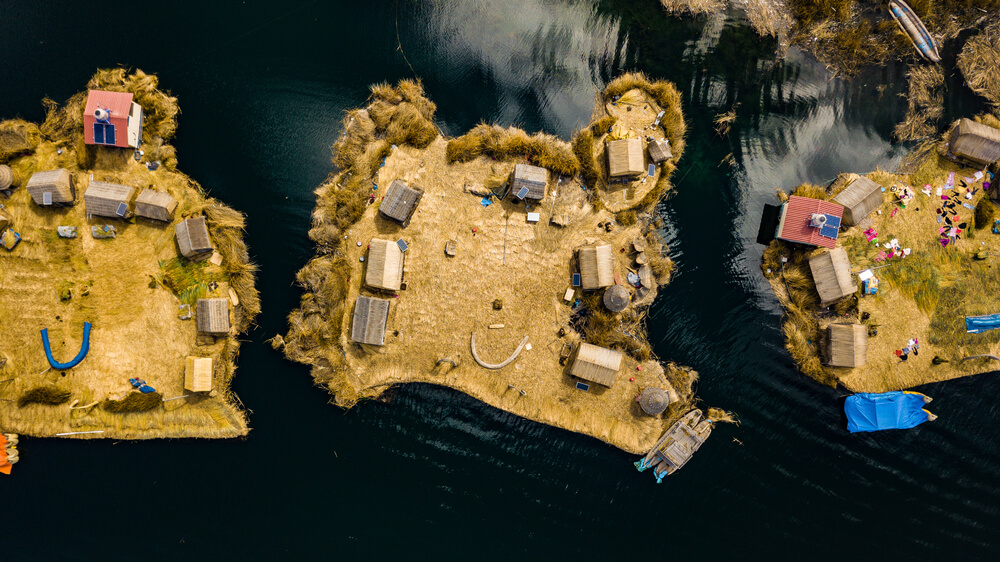 Aerial top view photo of floating islands on Lake Titicaca in Peru - a habitant of indigenous community Uros who are living on floating self-made islands made of totora plant
