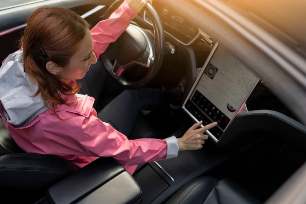 mature woman in an electric car touching GPS navigation to drive a car, controlling a car with a digital panel changing the autopilot mode, Smart electric car concept
