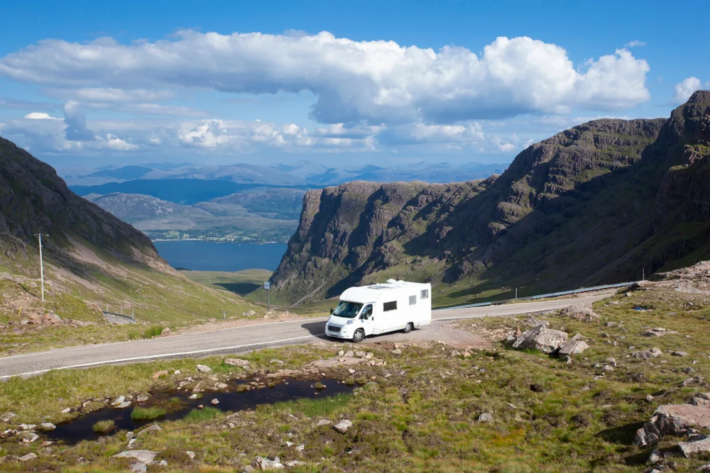Motorhome parked at the side of the road near Bealach na Ba and Applecross in summer in the Scottish Highlands with blue skies
