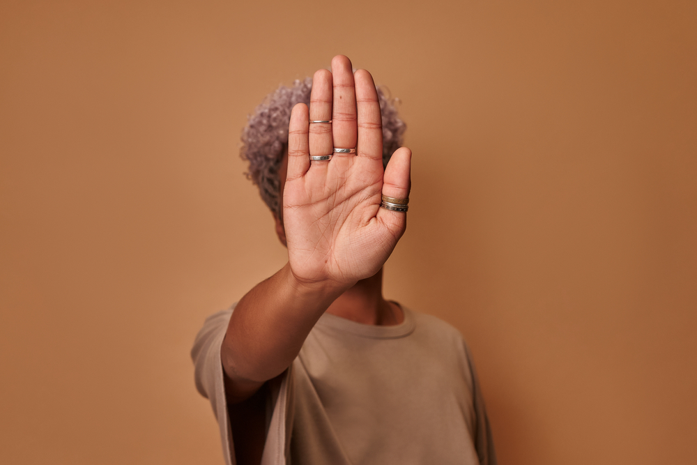 Serious African American woman covers herself with her palm, confidently shows prohibitory gesture stop and no signs shakes her head. Young ethnic woman against violence defends personal boundaries against Balancing Work and Personal Life.
