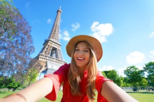 Selfie girl in Paris having fun with unlimited data France esim. Young tourist woman taking self portrait with Eiffel Tower in Paris.