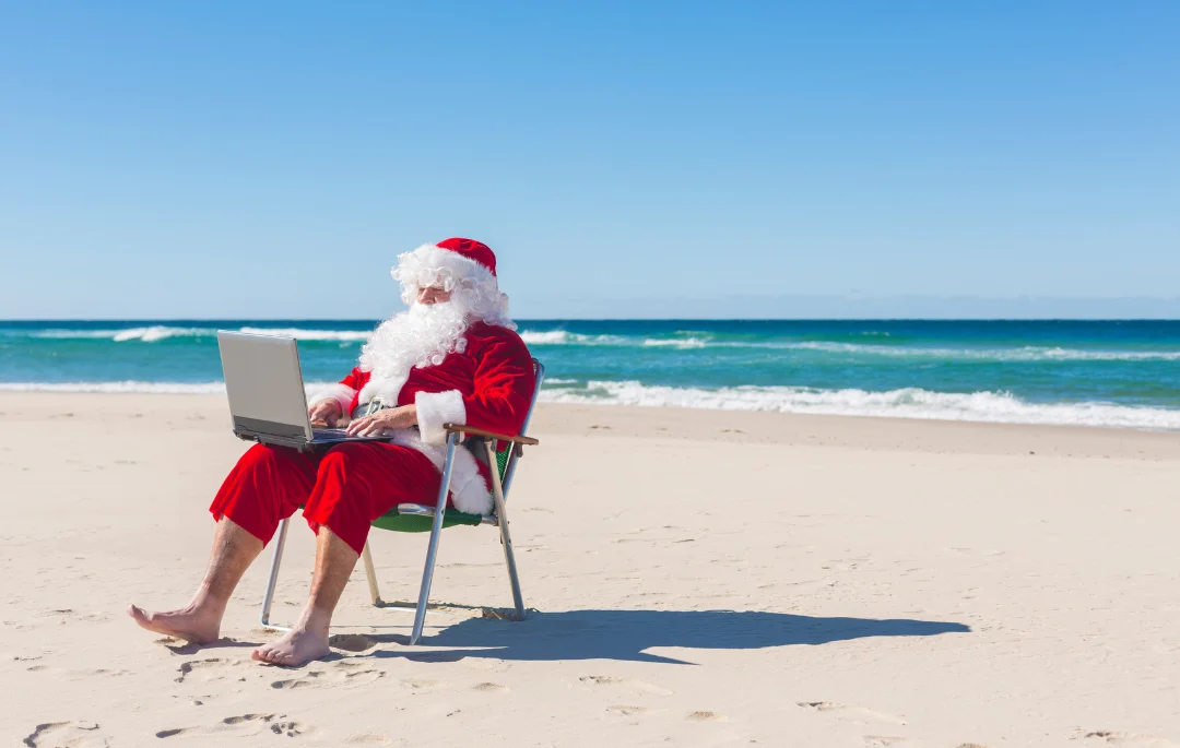 a man wearing santa clause costume and working on the seaside as a digital nomad