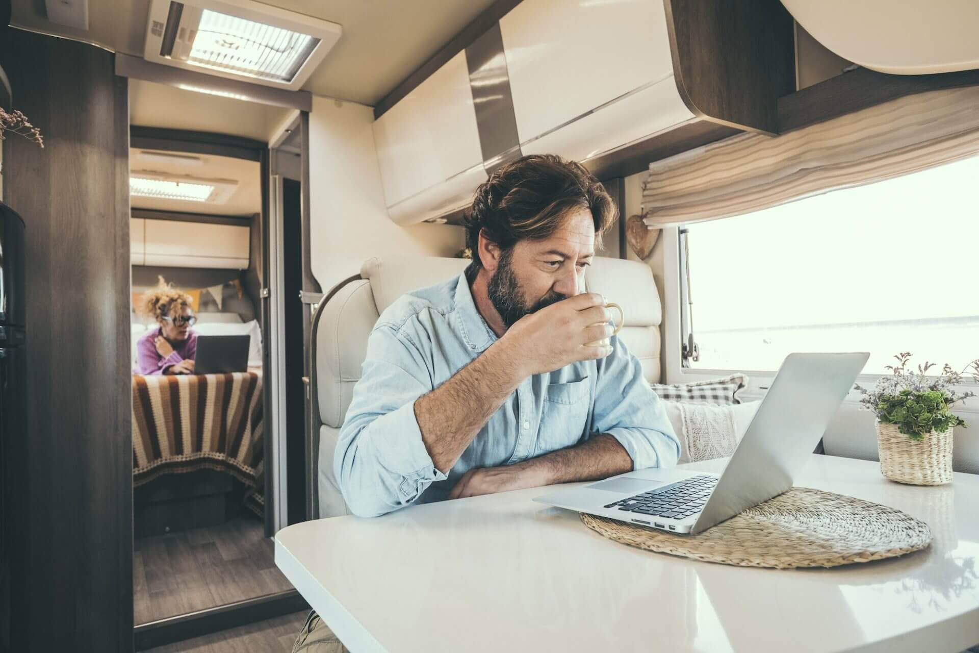 Couple use computer inside camper van during travel vacation or van life lifestyle.