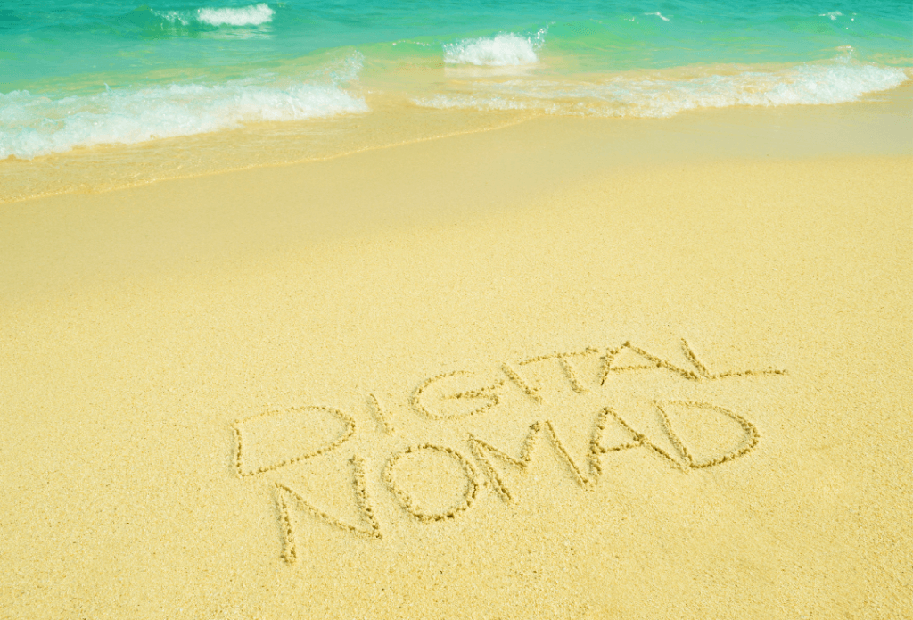 digital nomad written on the sand by seaside