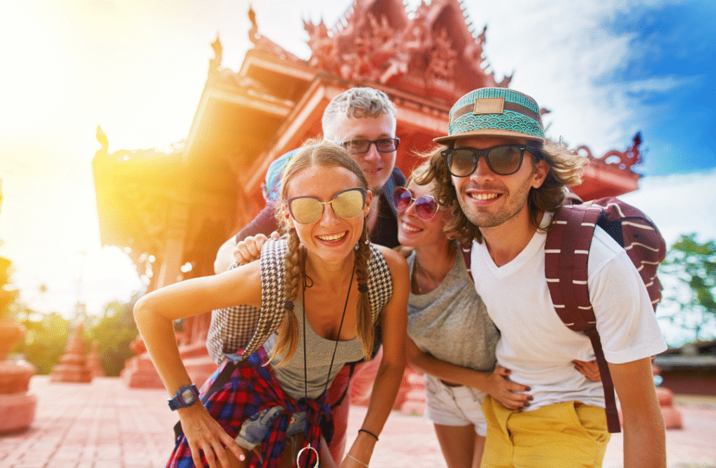 Happy group of international tourists posing in front of a traditional temple in Thailand on a sunny day – representing the best tourist friendly countries.