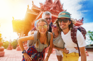 Happy group of international tourists posing in front of a traditional temple in Thailand on a sunny day – representing the best tourist friendly countries.