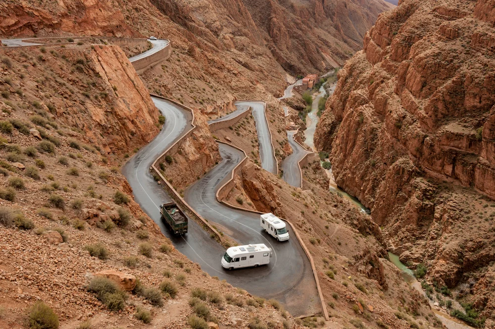 Truck and campervans climbing up the winding roads of the Dades gorge pass in Morocco.