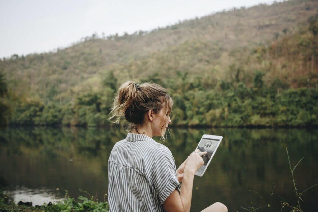 Woman alone in nature using a digital tablet internet connection and travel concept